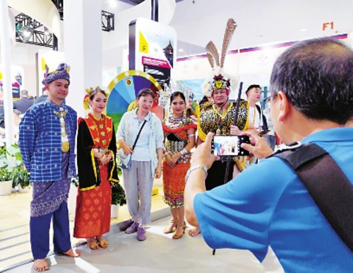 9月2日,国家会议中心展厅,马来西亚砂拉越州展馆的当地土著表演人员与参观者合影。